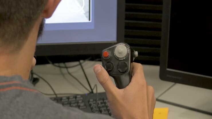 Back View Of A Retro Gamer Holding A Joystick While Talking On A Radiotelephone In Front Of A Computer - extreme close up