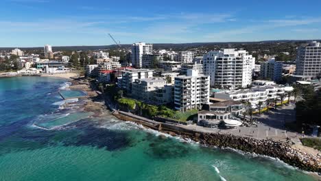 aerial cityscape of cronulla with sandy beach, turquoise water and skyline in sunlight, establishing pullback, sydney nsw australia