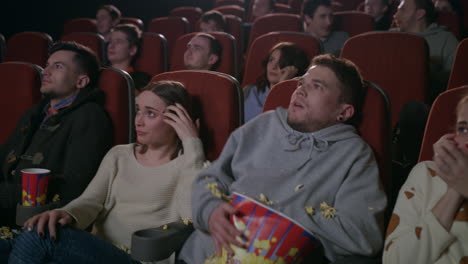 young guy scared while watching horror film in movie theatre