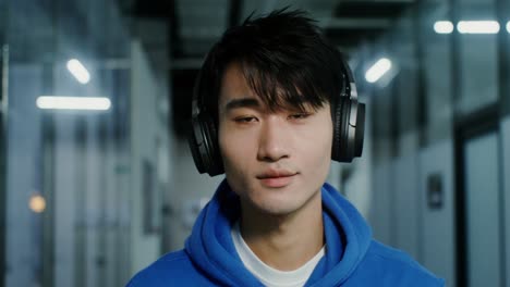 joven asiático con auriculares en una oficina moderna