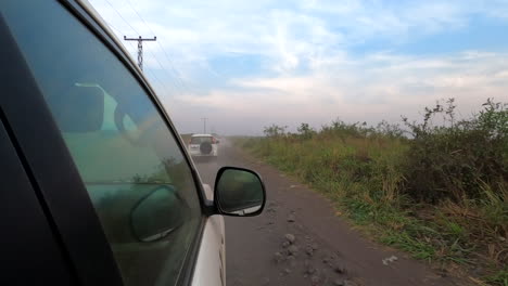 tres vehículos blancos conducen en convoy por un camino de tierra de tierras bajas en áfrica