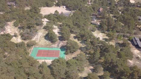 Una-Cancha-De-Tenis-Desierta-En-Un-Bosque-De-Pinos-Junto-Al-Océano