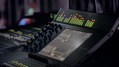 An audio sound mixer board's console audio meters pump during a live concert