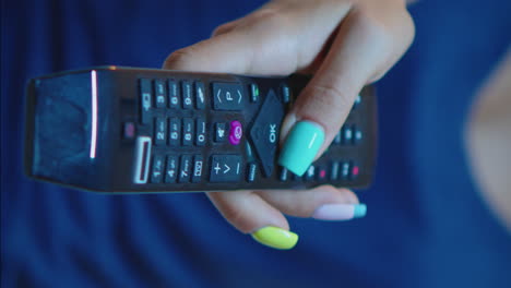 vertical video: close up of hand changing tv channels