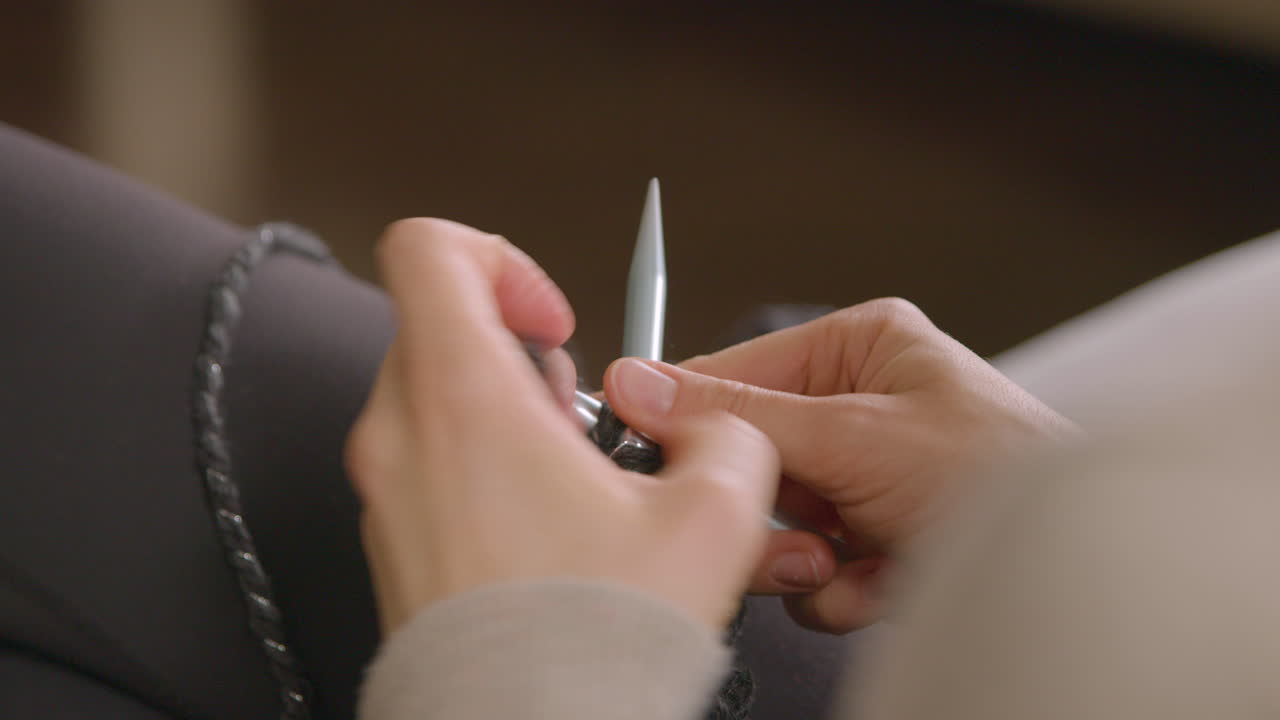 Woman learning to knit. Close up over the shoulder.
