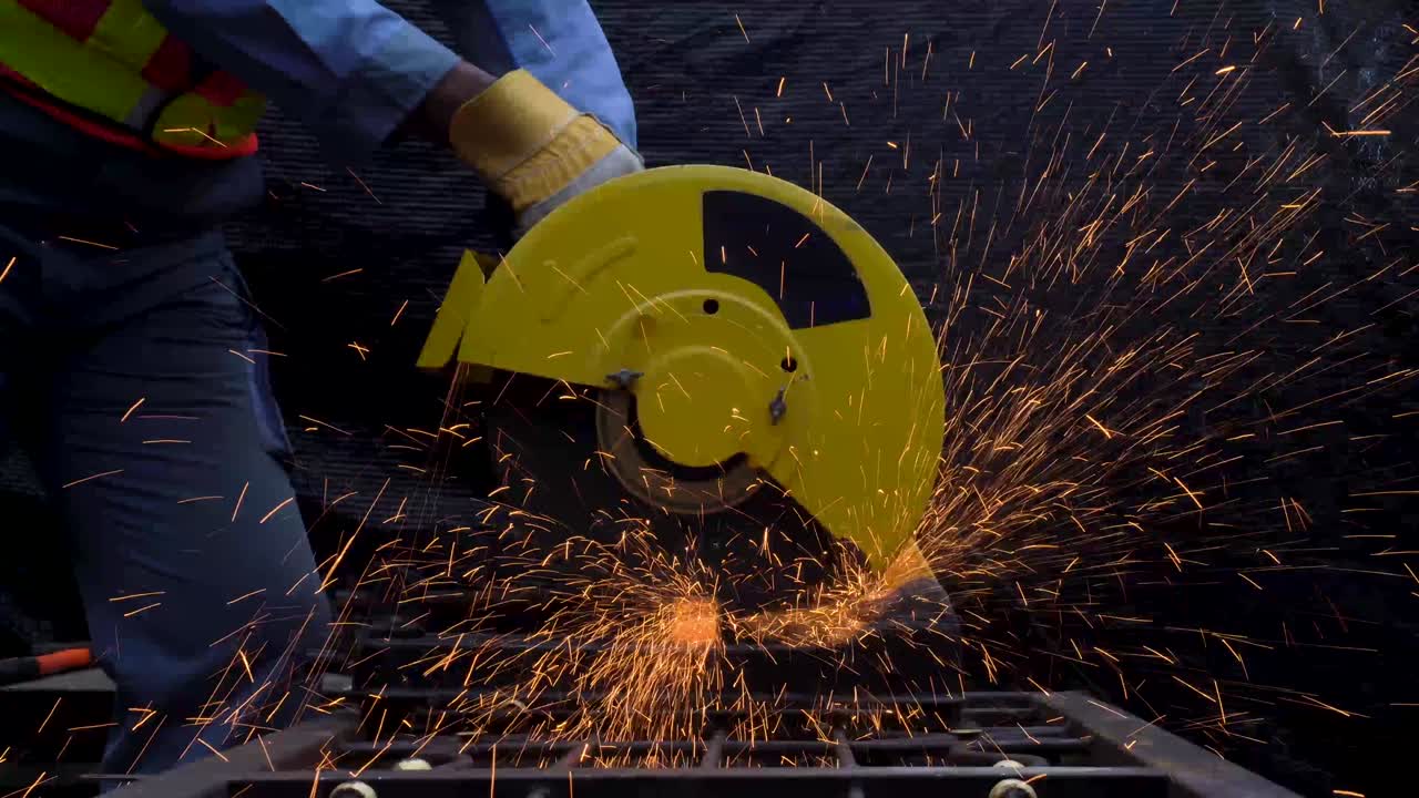 trabajador industrial en tela protectora azul usar máscara de seguridad, soldador profesional cortar estructura de acero con la emisión de chispas naranjas brillantes en la fábrica.