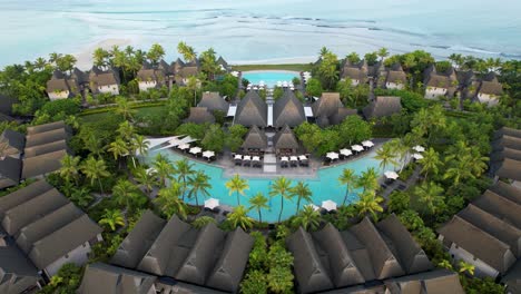 beachfront tropical luxury resort with pool and palm trees- aerial zoom in pan down