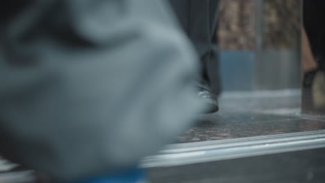 back view of young woman inside moving elevator with soft natural lighting highlighting urban environment, blurred glass panels reflect city elements