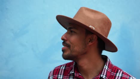 hombre colombiano sorprendido contra la pared azul