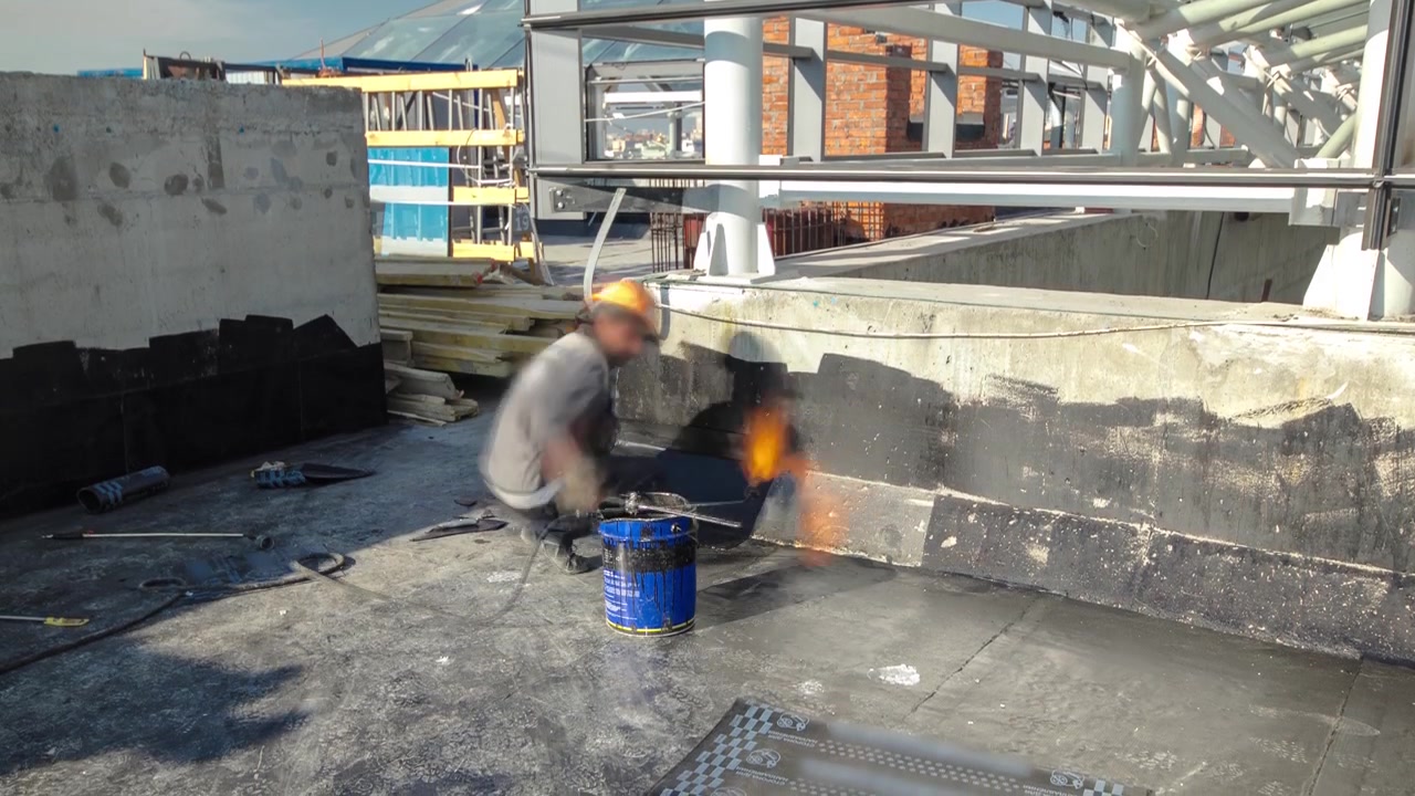 Takläggare installerar takpapp med uppvärmning och smältning av bitumenrulle med brännare på låga under takreparation timelapse. Byggprocess.