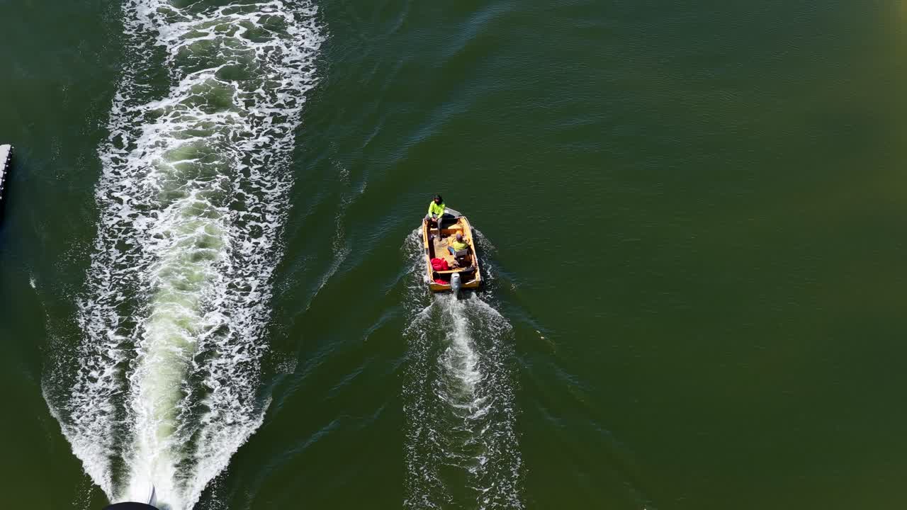 Due operai manovrano una piccola chiatta di manutenzione su un corso d'acqua verde, ripresi da un drone aereo