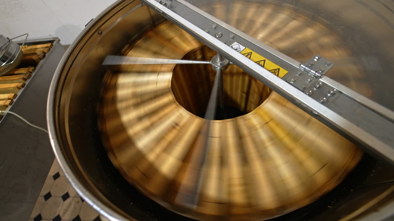 Opened lid to a metal barrel machine for honey extraction. Frames with honeycombs are rotated in the centrifuge apparatus. Top view.