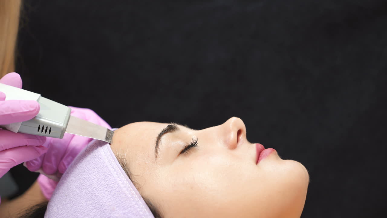 Woman receiving cleansing therapy with a professional ultrasonic equipment in cosmetology office.