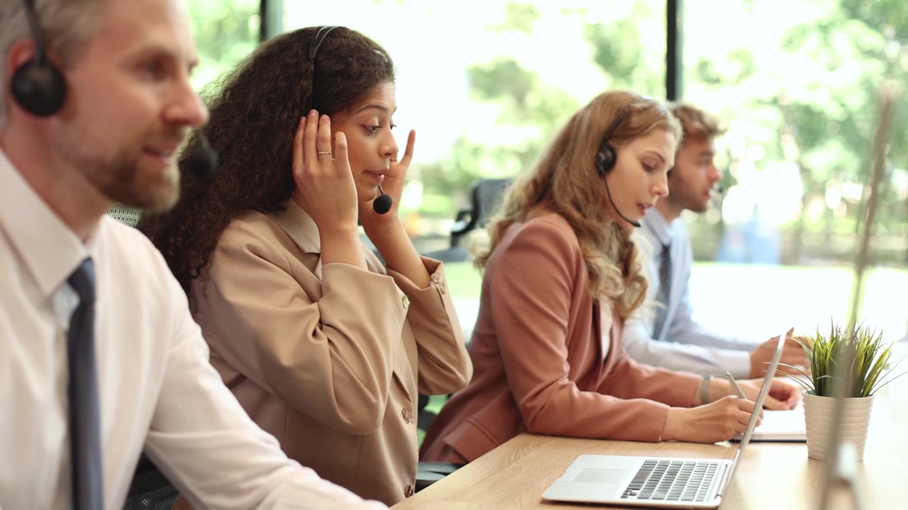 Diversi operatori di call center lavorano sui laptop con cuffie in ufficio