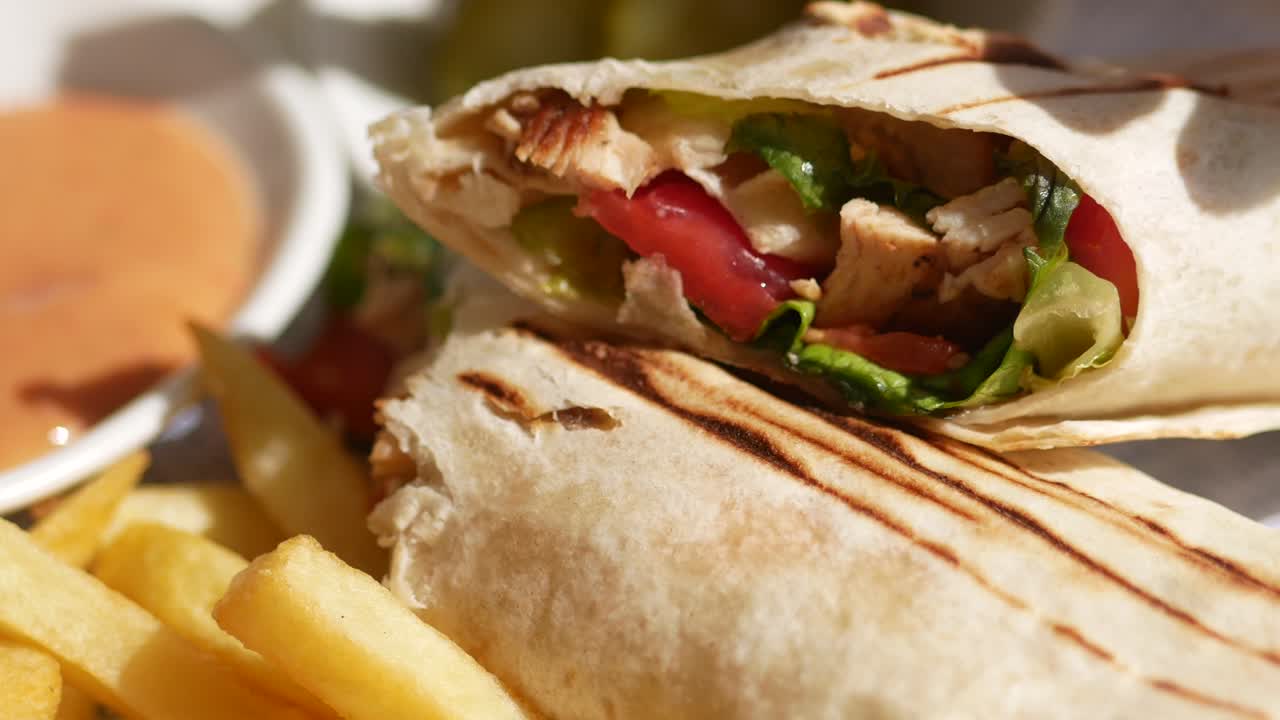 primer plano de una envoltura de shawarma con papas fritas y pepinillos