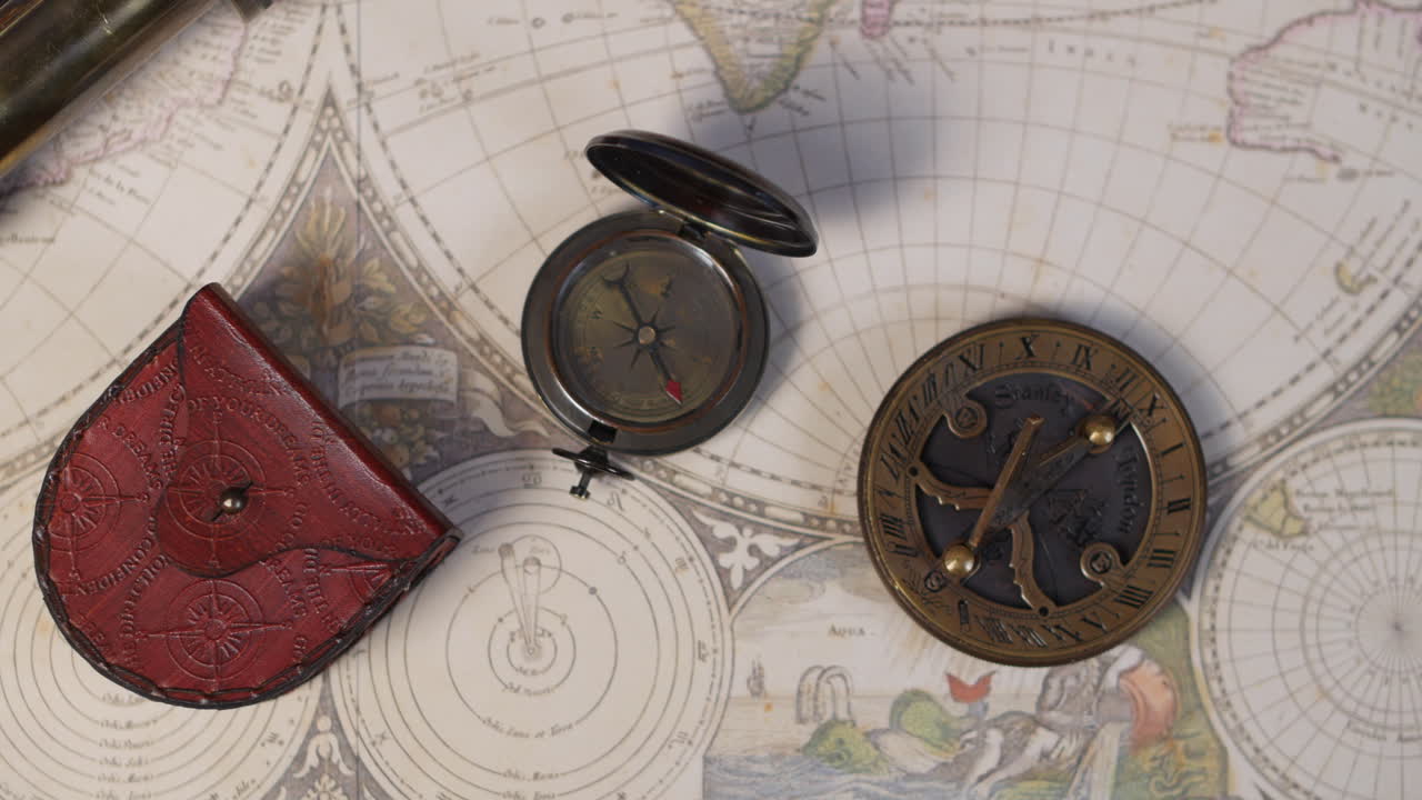 A selection of antique nautical instruments including sundial and compass on a vintage world map