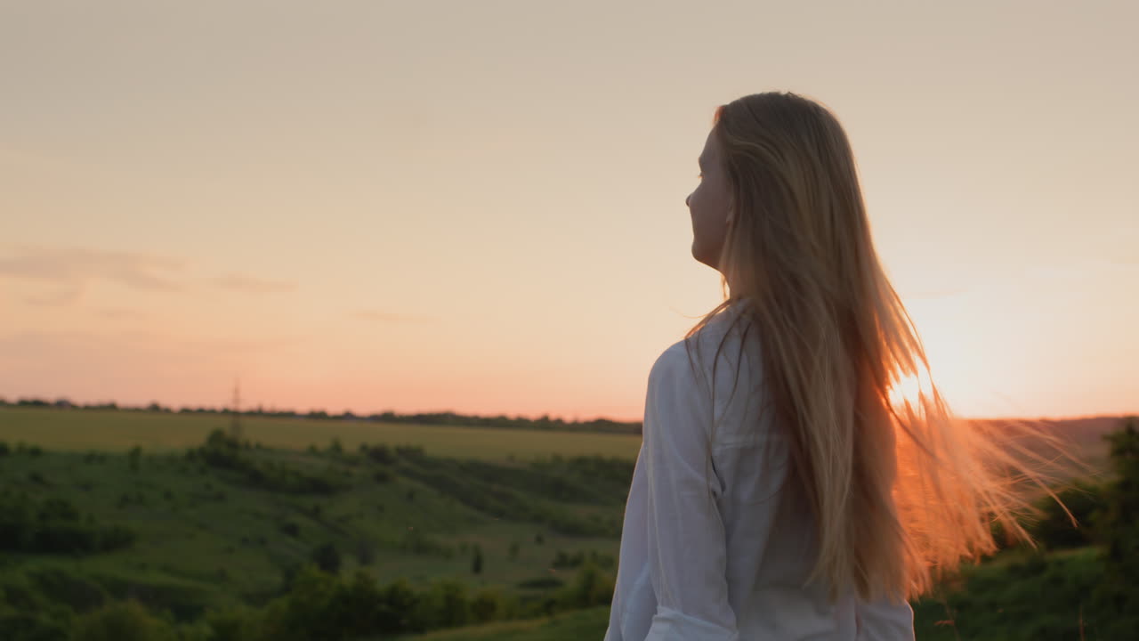 Teenage girl turns her head and long hair at sunset. Slow motion video