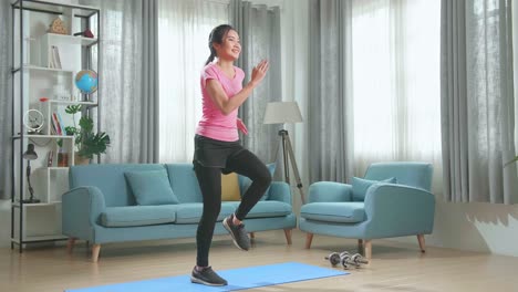hermosa chica de fitness atlética asiática en ropa deportiva está corriendo enérgicamente en su lugar en su sala de estar con interior moderno