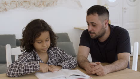 hijo caucásico y padre haciendo la tarea juntos en casa.
