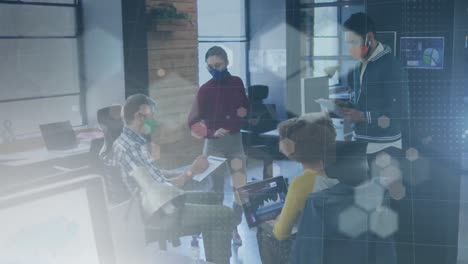 Animation-of-network-of-hexagons-over-colleagues-in-face-masks-working-in-office