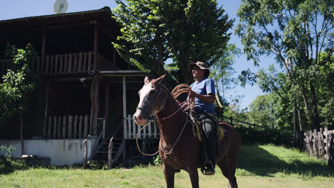 Uomo a cavallo che tiene una corda in un paesaggio rurale