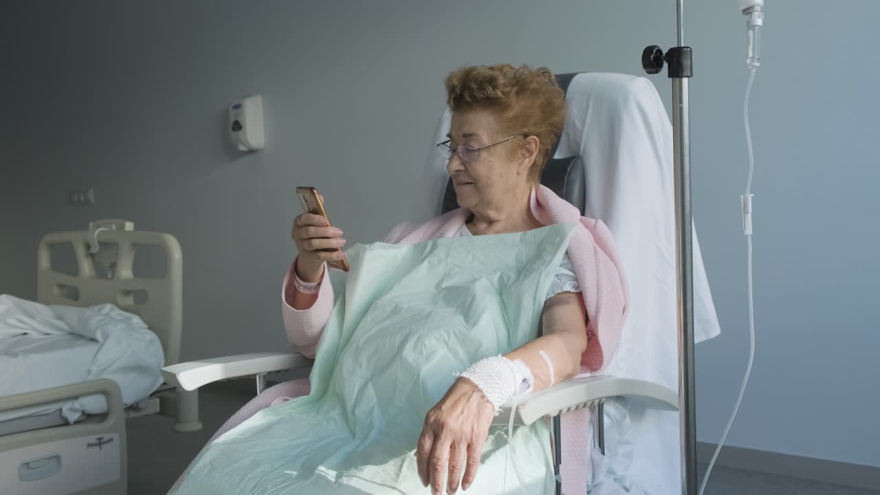 paciente anciana sentada en la silla mira en su celular