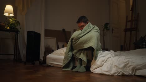 man wrapped in blanket on the floor