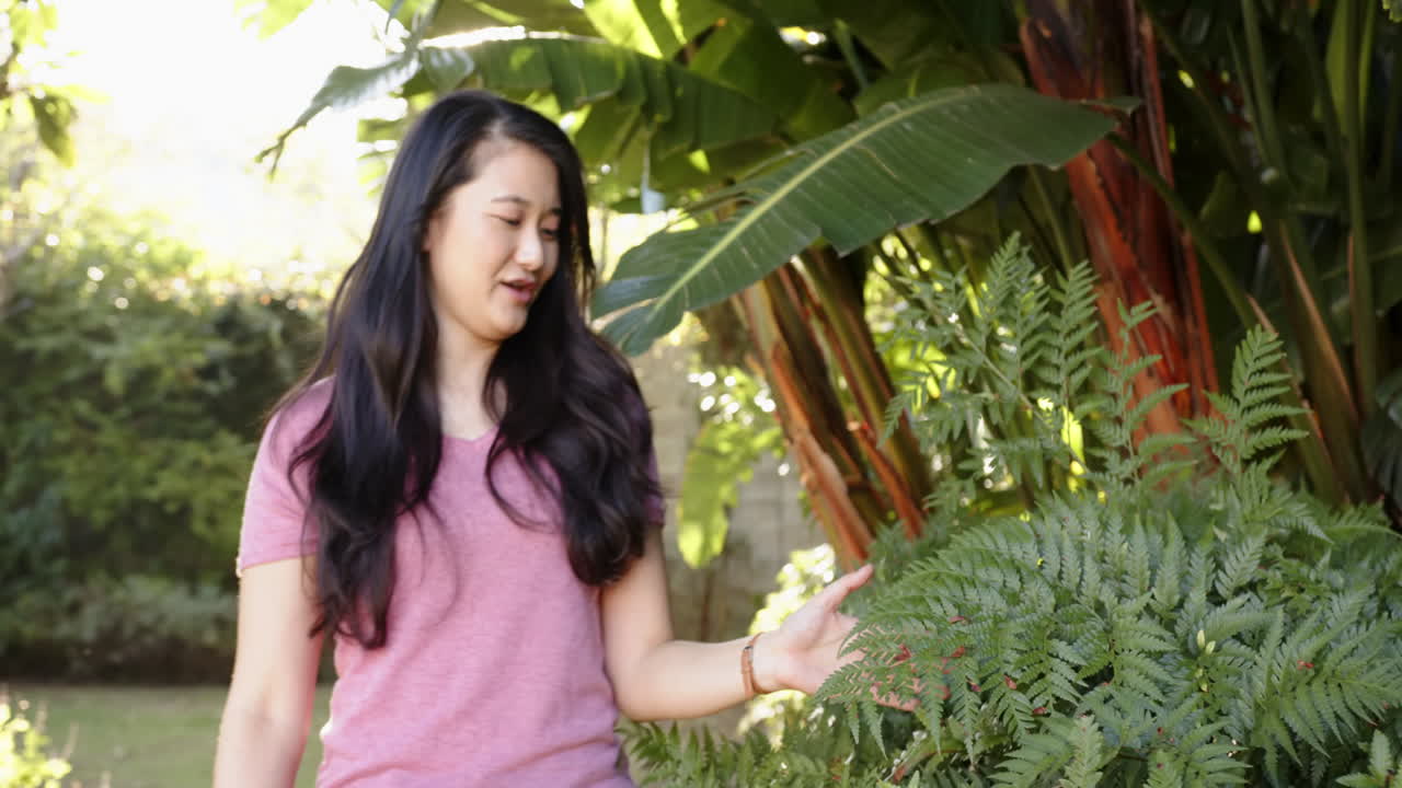 Exploring garden, woman enjoying nature and touching plants