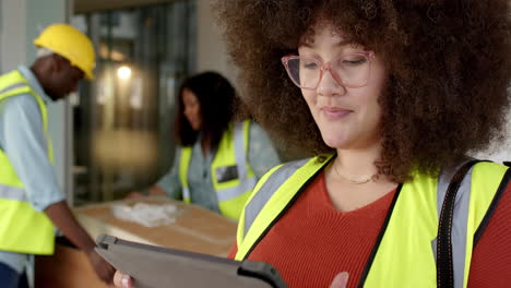 Smiling-casual-biracial-female-architect-with-tablet-in-office,-slow-motion,-copy-space