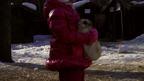 little baby girl holds a rabbit. girl talks to rabbit.  a sunny spring day.