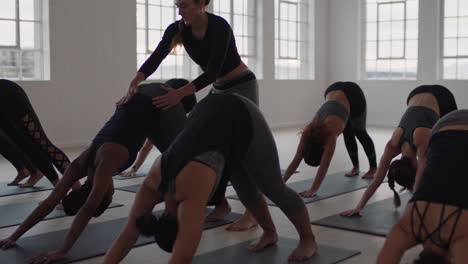 Instructor-De-Clase-De-Yoga-Enseñando-Pose-De-Perro-Boca-Abajo-A-Un-Grupo-De-Mujeres-Practicando-Disfrutando-De-Un-Estilo-De-Vida-Saludable-Haciendo-Ejercicio-En-Un-Gimnasio-Al-Amanecer