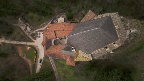 Aerial-drone-top-down-backward-over-San-Romedio-Sanctuary-perched-on-rocky-outcrop-of-Predaia-in-Northern-Italy