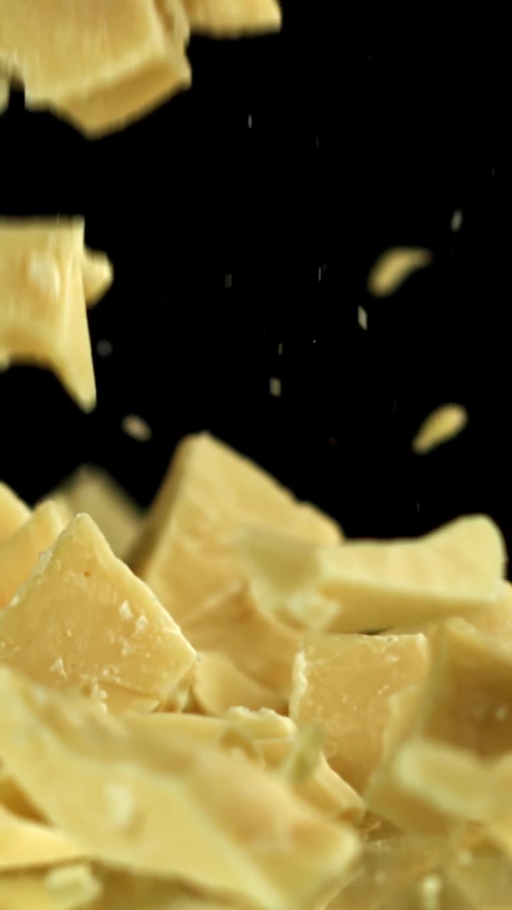 White Chocolate Pieces Falling in Slow Motion on Black Background