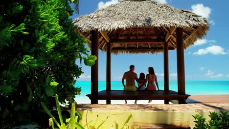 caucasian family sitting in a tiki beach hut