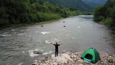 A Fisherman Fishes by Spinning a View of a Mountain River and a Green Tent a Fisherman Fishes by Spinning a View of a Mountain River and a Green Tent Shooting from a Drone