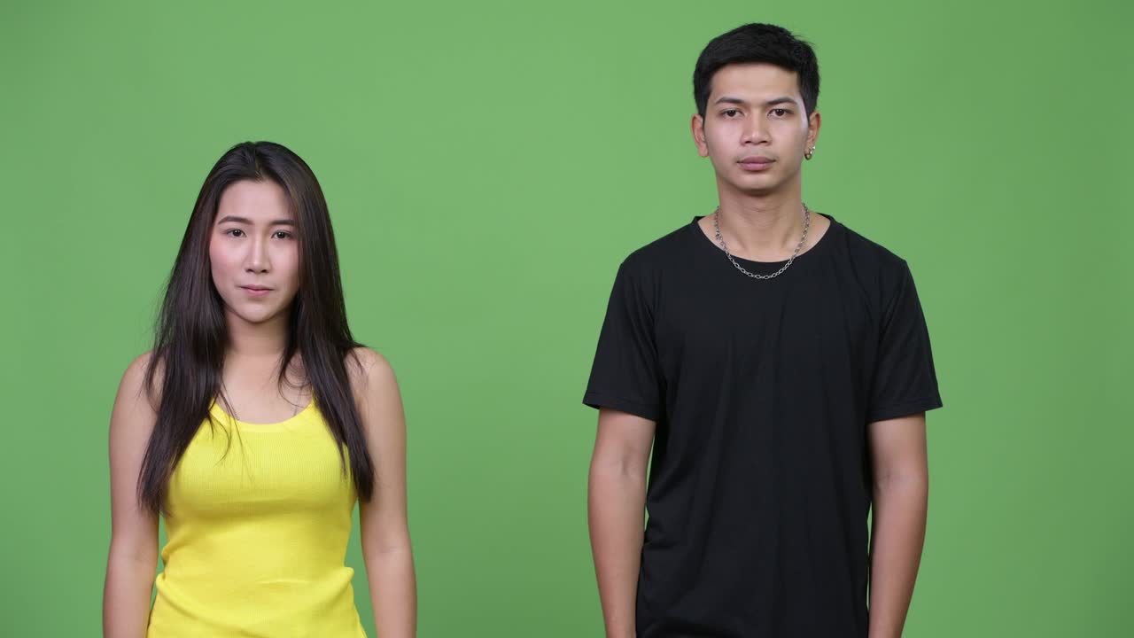 젊은 아시아 커플이 함께 무언가를 보여주고 있습니다.