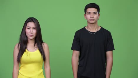 una joven pareja asiática mostrando algo juntos.