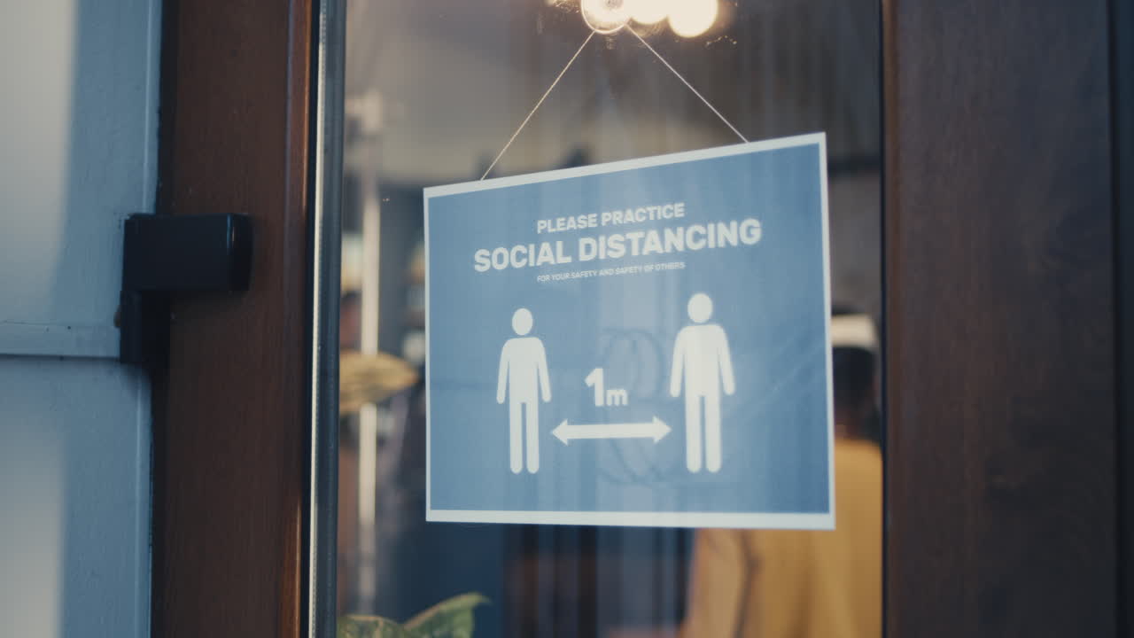 Person hanging a social distancing sign on a shop door