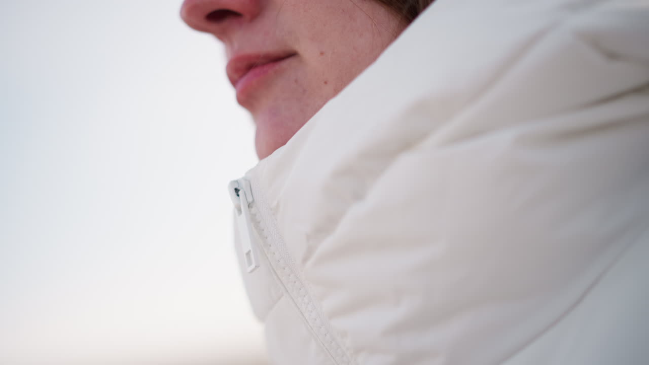 Manicured hand closing up zip on fluffy winter coat with gleaming nails, close detail of polished manicure against quilted fabric in soft winter light, stylish cold outfit accessory motion captured