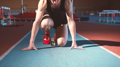 portrait of a focused young male athlete on the starting line and looking at camera on an indoor track