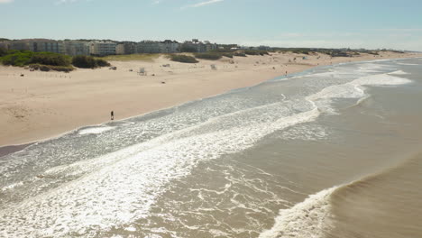 Aerial-parallax-of-a-person-walking-free-on-the-beach-in-the-morning