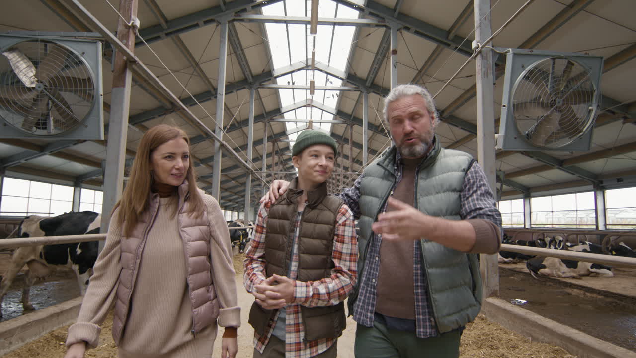 Parents Showing Teenage Son Around Dairy Farm