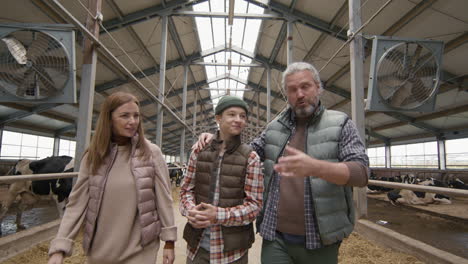 parents showing teenage son around dairy farm
