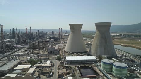 aerial footage of a large scale oil refinery with smoke stacks and petroleum storage tanks