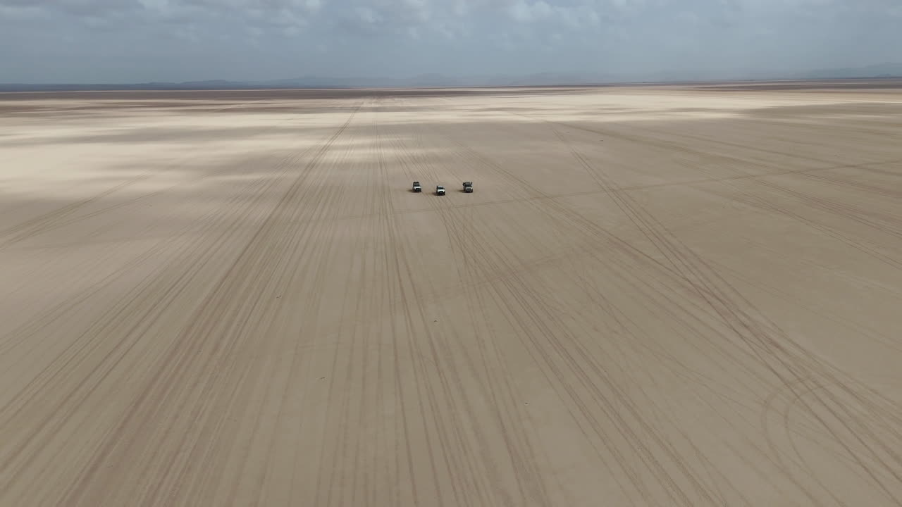 Vista aerea cinematografica di un'avventura di guida nel deserto attraverso un paesaggio aspro e isolato, ampie riprese aeree con drone in rotazione. Gibuti, Africa.