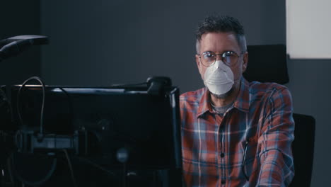 man in wheelchair working at computer with mask