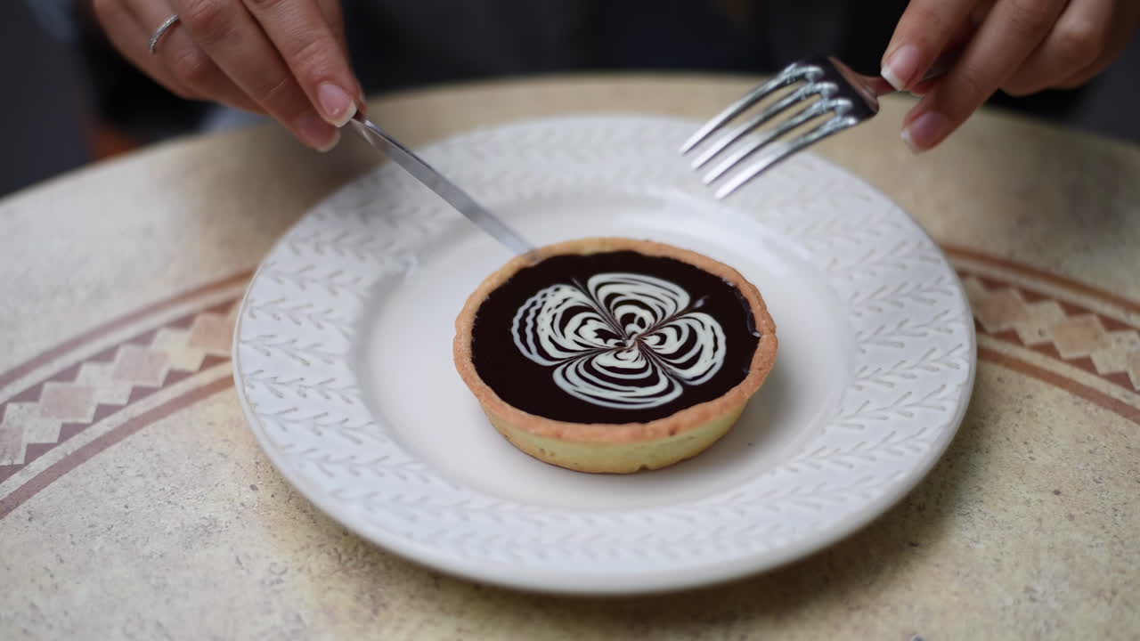 Close up of a woman eating a chocolate tart on a table a terrace