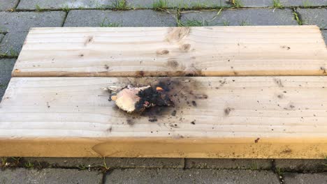 Nahaufnahme-Eines-Kleinen-Feuers,-Das-Papier-Auf-Planken-Brennt-Und-Aussterbt