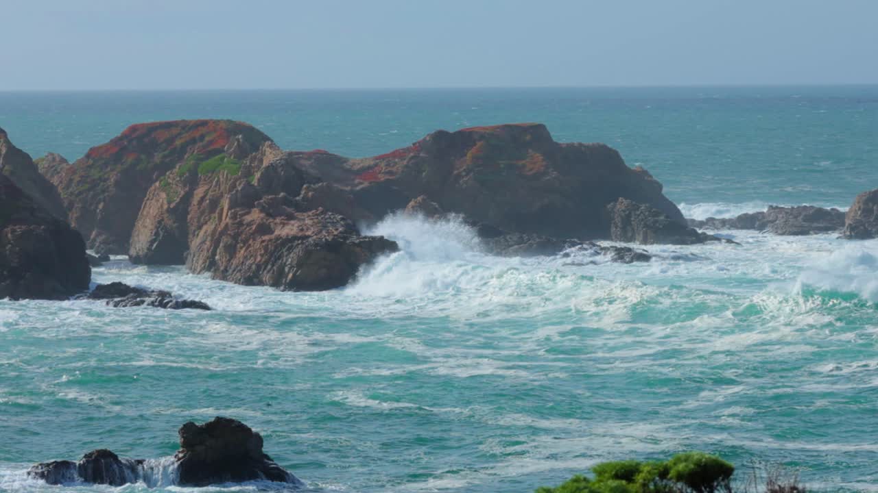 grandes olas rompiendo contra una isla rocosa en la costa de big sur en garrapata, acantilados cubiertos de hielo rojo en cámara lenta