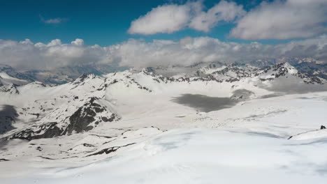 air flight through mountain clouds over beautiful snow-capped peaks of mountains and glaciers.